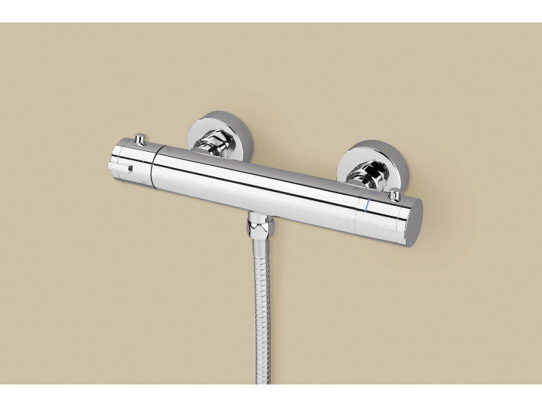 Chromen thermostatische douchekraan met flexibele slang op een beige muur.