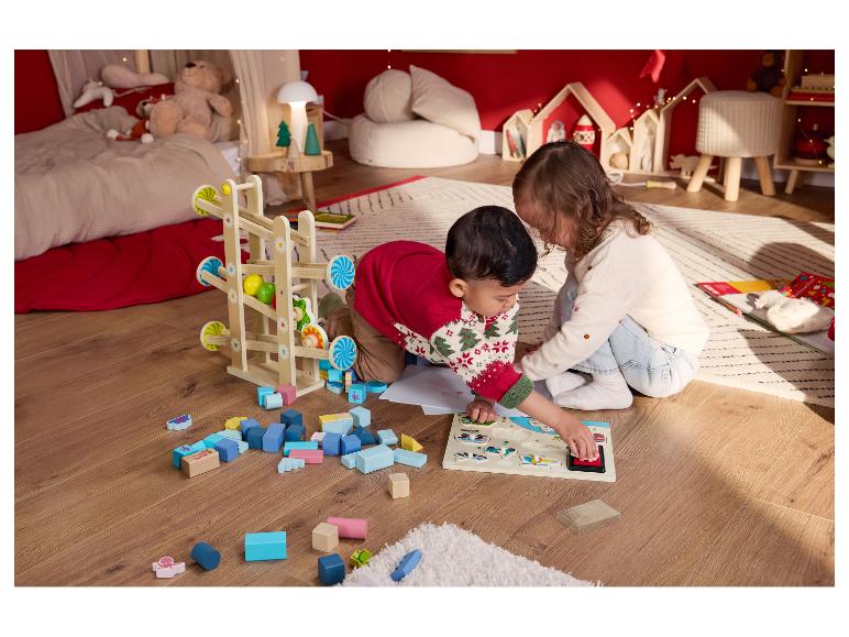 Twee kinderen spelen op de vloer met houten speelgoed en een puzzel.