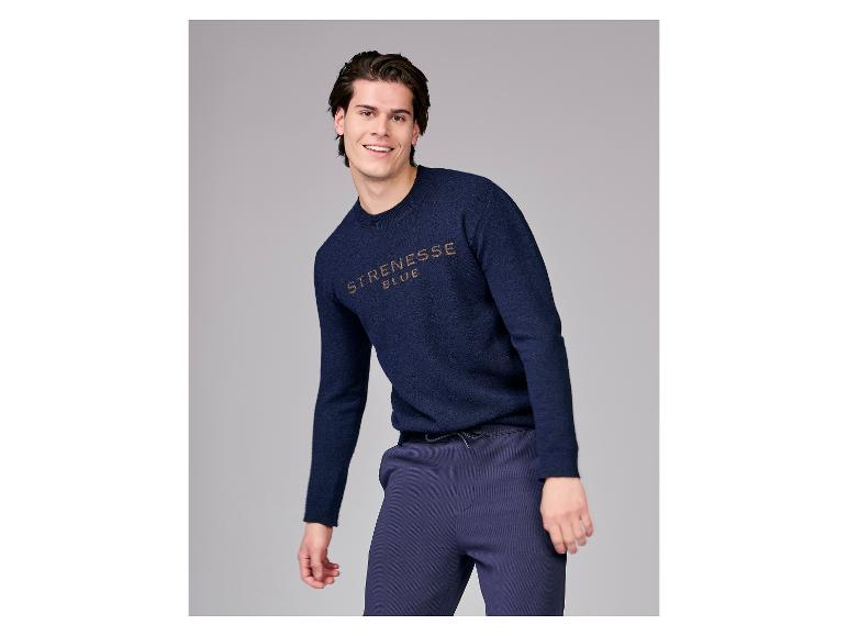 Lachende man in een donkerblauwe trui en donkerblauwe broek.