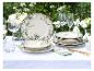 Elegante buitentafel met bloemmotief servies, gouden bestek en witte bloemen.