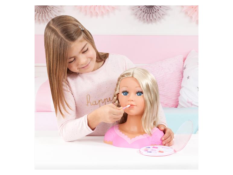 Meisje schminkt een poppenhoofd met blond haar en blauwe ogen.