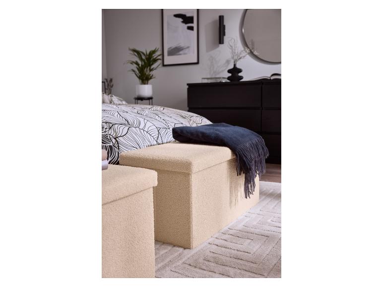 Twee beige opbergpoefs met een donkerblauwe plaid in een slaapkamer.