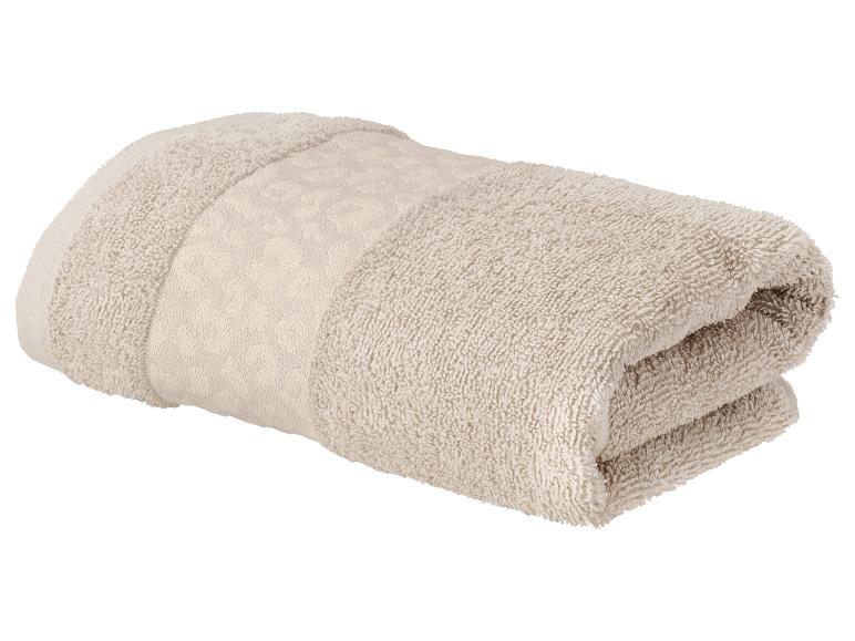 Opgevouwen beige handdoek met decoratieve band