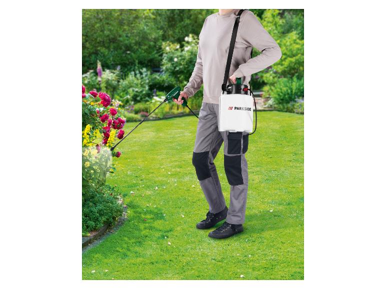 Persoon gebruikt een PARKSIDE drukspuit in een bloeiende tuin.