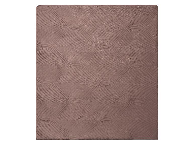 Bruine deken of sprei met een golvend en geometrisch doorgestikt patroon.