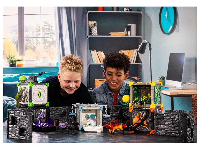 Twee jongens spelen met een speelset met monsters en grotten.