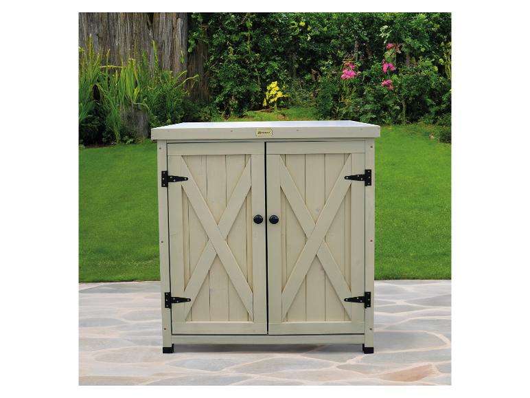 Houten kast met twee deuren en zwarte handgrepen op een betegeld terras in een tuin.