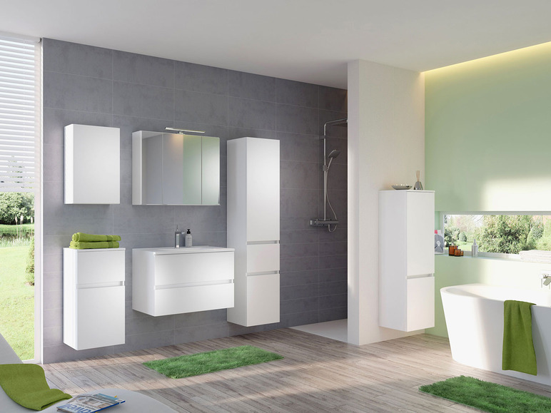 Badkamer met witte badkamerkasten, een wastafel en een bad.