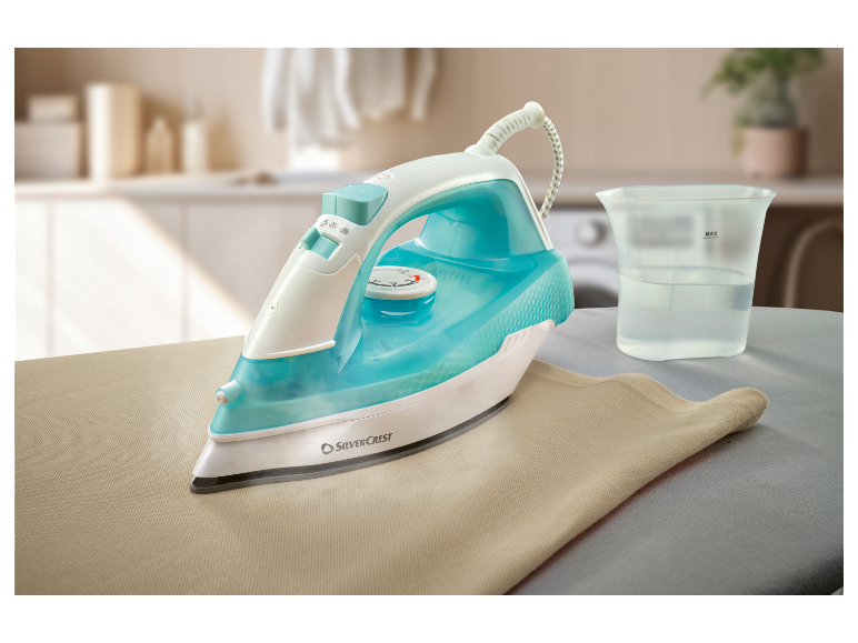 Een Silvercrest stoomstrijkijzer strijkt een beige stof op een strijkplank.