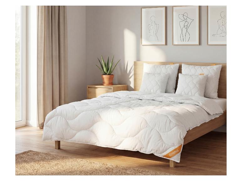 Slaapkamer met een bed met wit gewatteerd beddengoed, kussens en een houten hoofdbord.