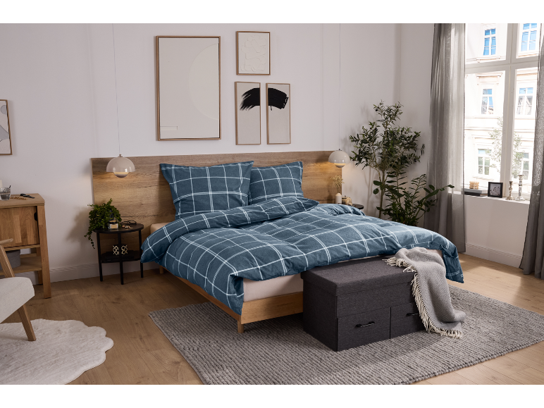 Slaapkamer met blauw geruit beddengoed, houten hoofdbord en nachtkastjes.