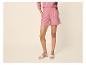 Vrouw in roze overhemd en korte broek, met beige sandalen.