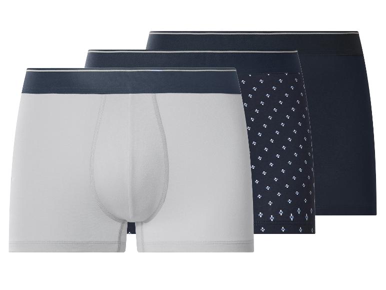 Drie herenboxershorts: één lichtgrijs, één donkerblauw met patroon en één effen donkerblauw.