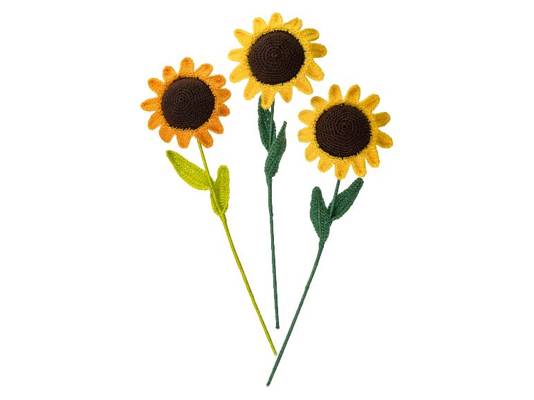 Drie gehaakte zonnebloemen met gele bloemblaadjes en bruine centra op witte stelen