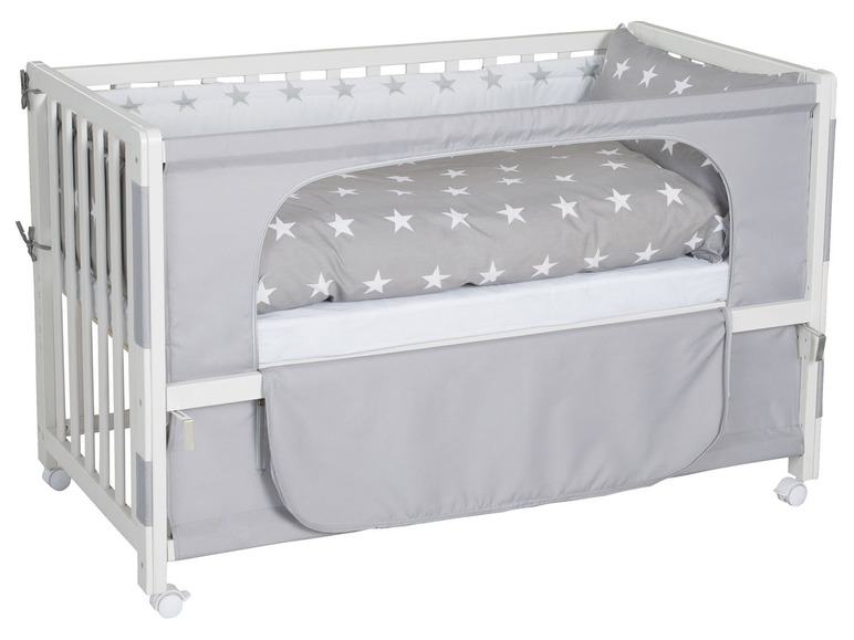 Een wit babybedje met een grijs sterrenthema.