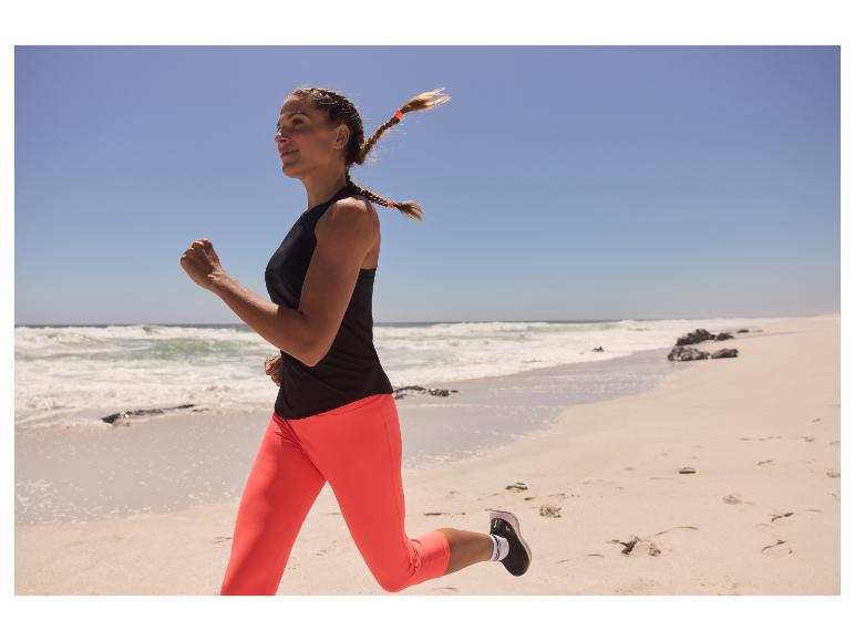 Vrouw joggend in leggings en top op het strand.