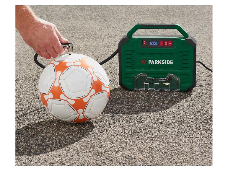 Man pompt een voetbal op met een groene luchtcompressor.