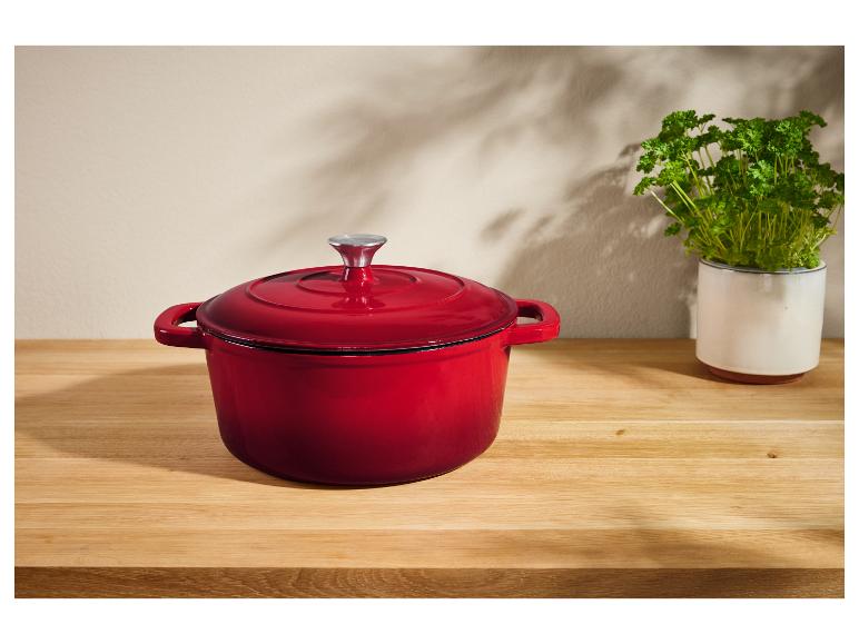 Rode gietijzeren pot op een houten tafel.