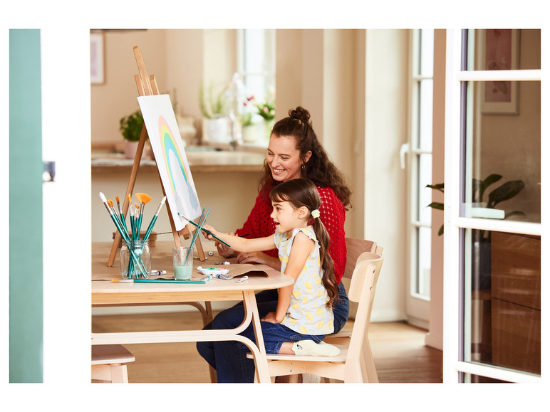 Een moeder en dochter schilderen een regenboog op een ezel.