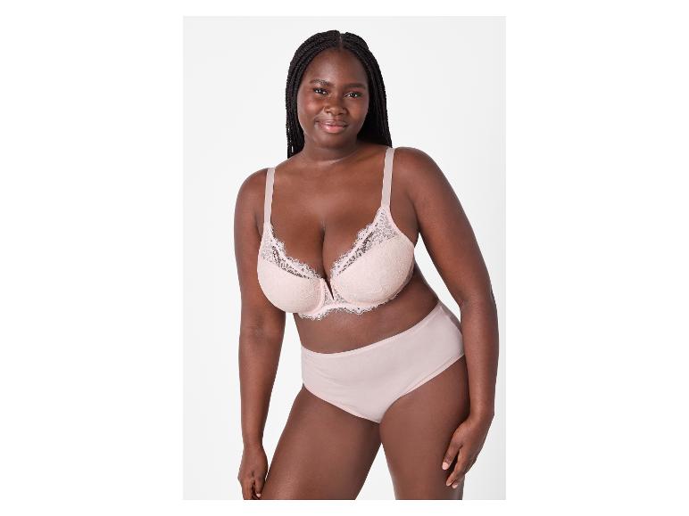 Lachende vrouw in lichtroze kanten beha en slip.