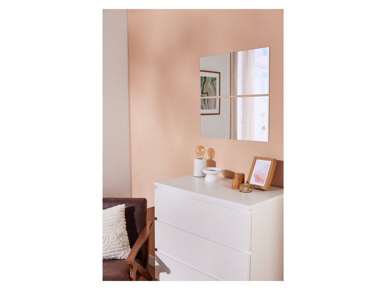 Vierkante spiegels boven een witte commode in een moderne woonkamer.