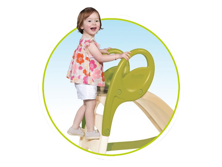 Lachend kind klimt op een groene glijbaan.