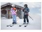 Twee kinderen in ski-uitrusting en CRIVIT-helmen voor een houten hut.