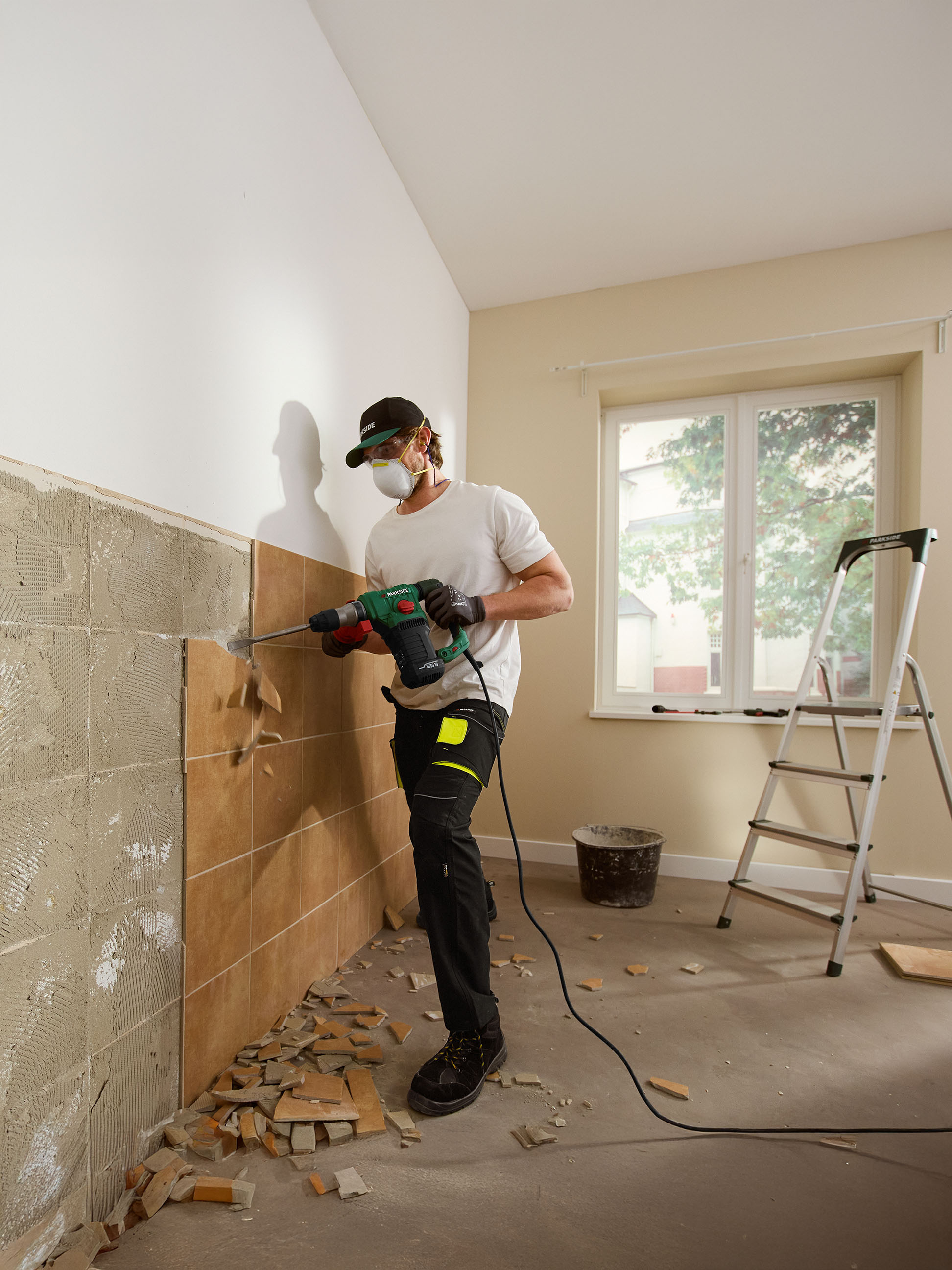 Man verwijdert tegels van een muur met een Parkside boorhamer.