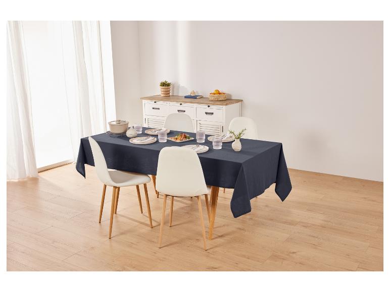 Tafelkleed, stoelen en servies op een eettafel.