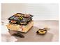 Raclette grill met bamboe basis, grillplaat en individuele pannetjes met eten.
