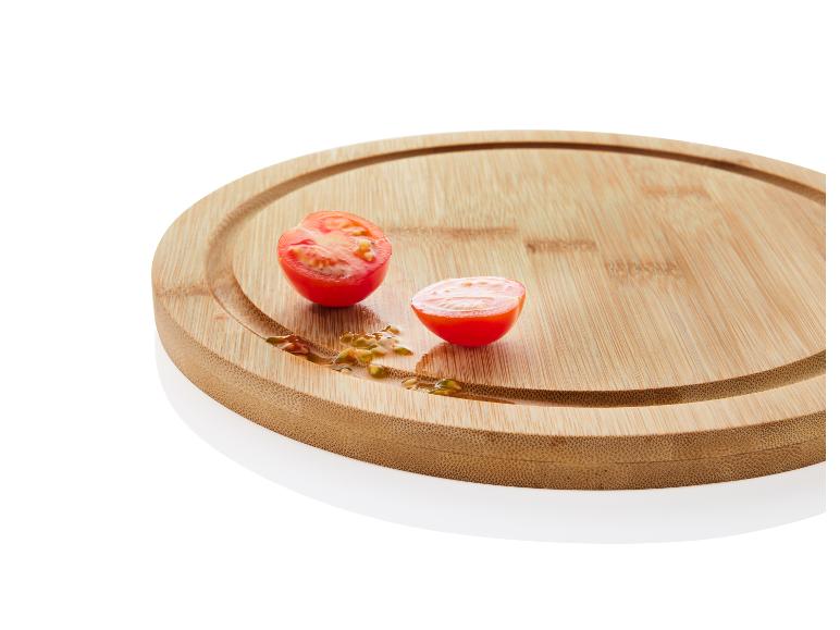 Twee halve cherrytomaatjes op een houten snijplank.