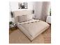 Beige bed met hoofdbord, gestreept beddengoed en kussens met tekst, naast nachtkastjes.