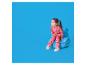 Klein meisje in roze pyjama met teckelpatroon zit op een blauw kussen.