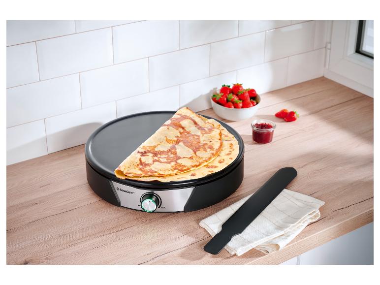 SilverCrest crêpe maker met crêpes, aardbeien en jam op een houten aanrecht.