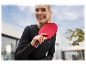 Een lachende vrouw houdt een rode tafeltennisbat vast.