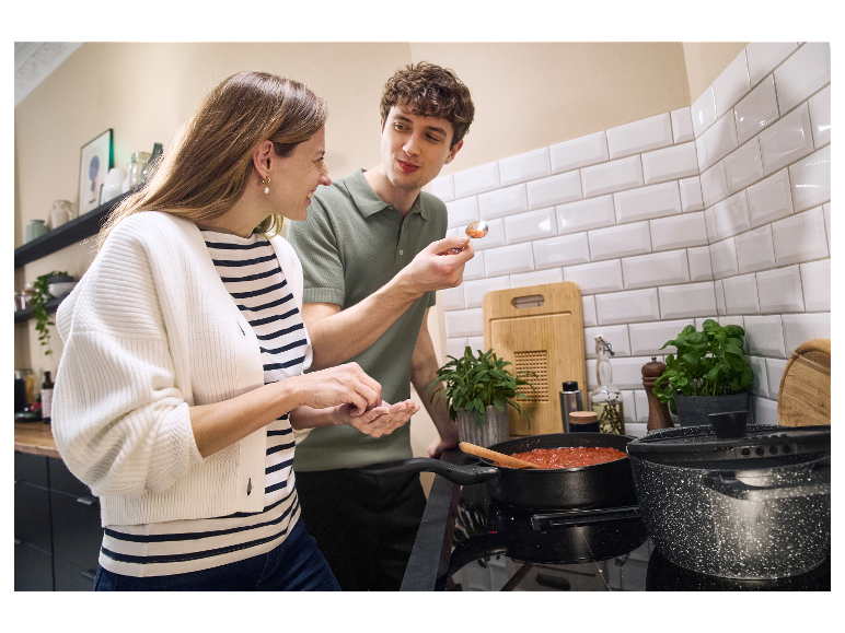 Een stel in de keuken maakt tomatensaus in een pan.