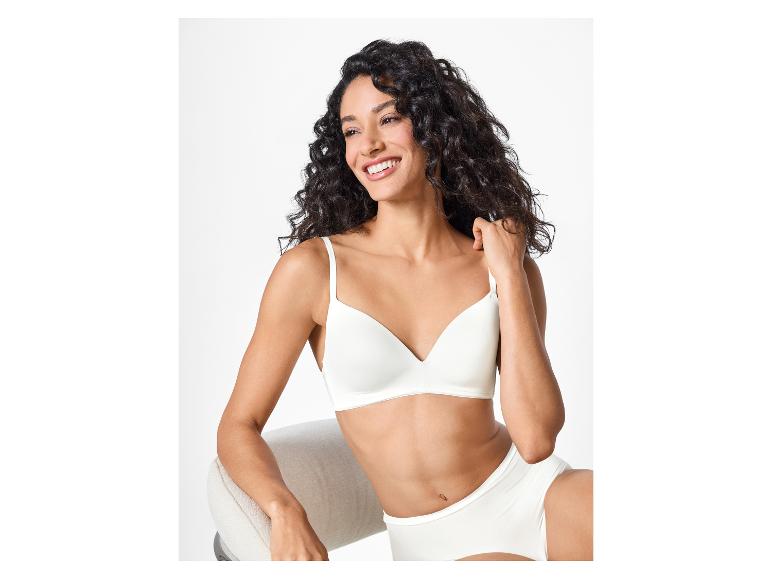 Vrouw in witte bh en slip, zittend en lachend.