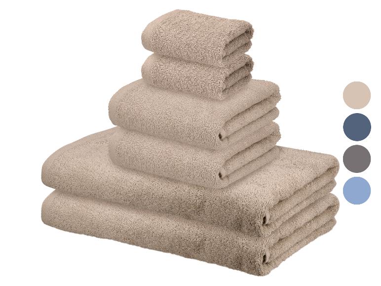 Een set beige handdoeken in verschillende maten gestapeld, met kleurstalen ernaast.