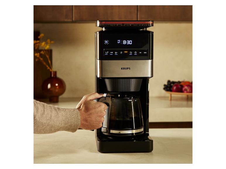 Koffiezetapparaat met digitaal display en kan, bediend door een persoon.