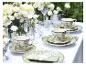 Elegante buitentafel met witte bloemen en groen-wit gedessineerd servies.