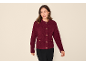 Vrouw in bordeauxrode bouclé vest met gouden knopen en zwarte broek.