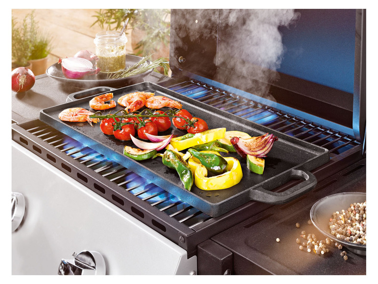 Gegrilde garnalen, groenten en een gietijzeren grillplaat op een gasgrill.