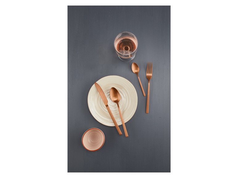 Een bord met bestek en een glas rosé wijn.