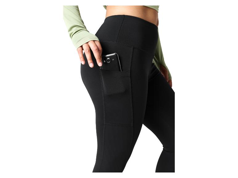 Vrouw in zwarte legging met telefoon in zijzak en een lichtgroene top