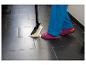 Persoon met stoommop maakt vloer schoon, draagt roze sandalen en blauwe broek.