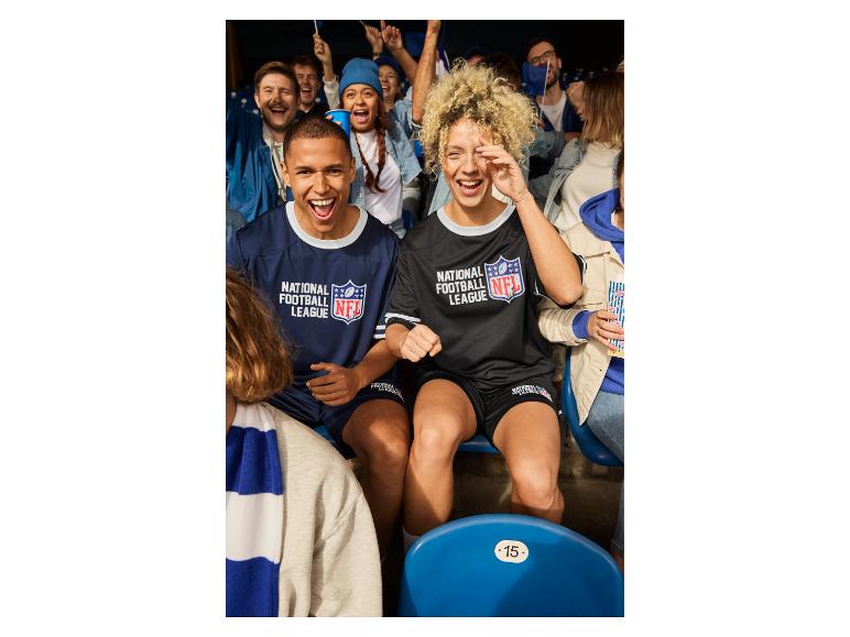 Man en vrouw in NFL-shirts zitten in een stadion met andere fans.