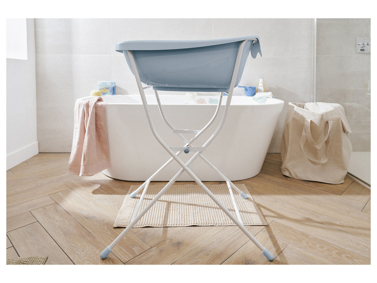 Een blauwe babybad in een badkamer met houten vloer.