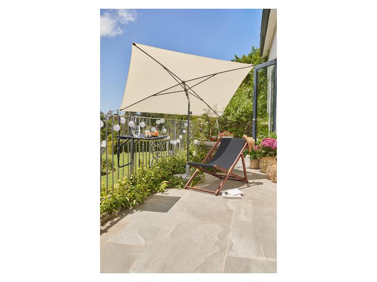 Balkon met een crèmekleurige parasol, een zwarte strandstoel en een tafeltje met snacks.