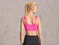 Een vrouw draagt een roze sportbeha en zwarte leggings.