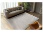 Moderne woonkamer met beige bank, golvend tapijt en leren fauteuil.